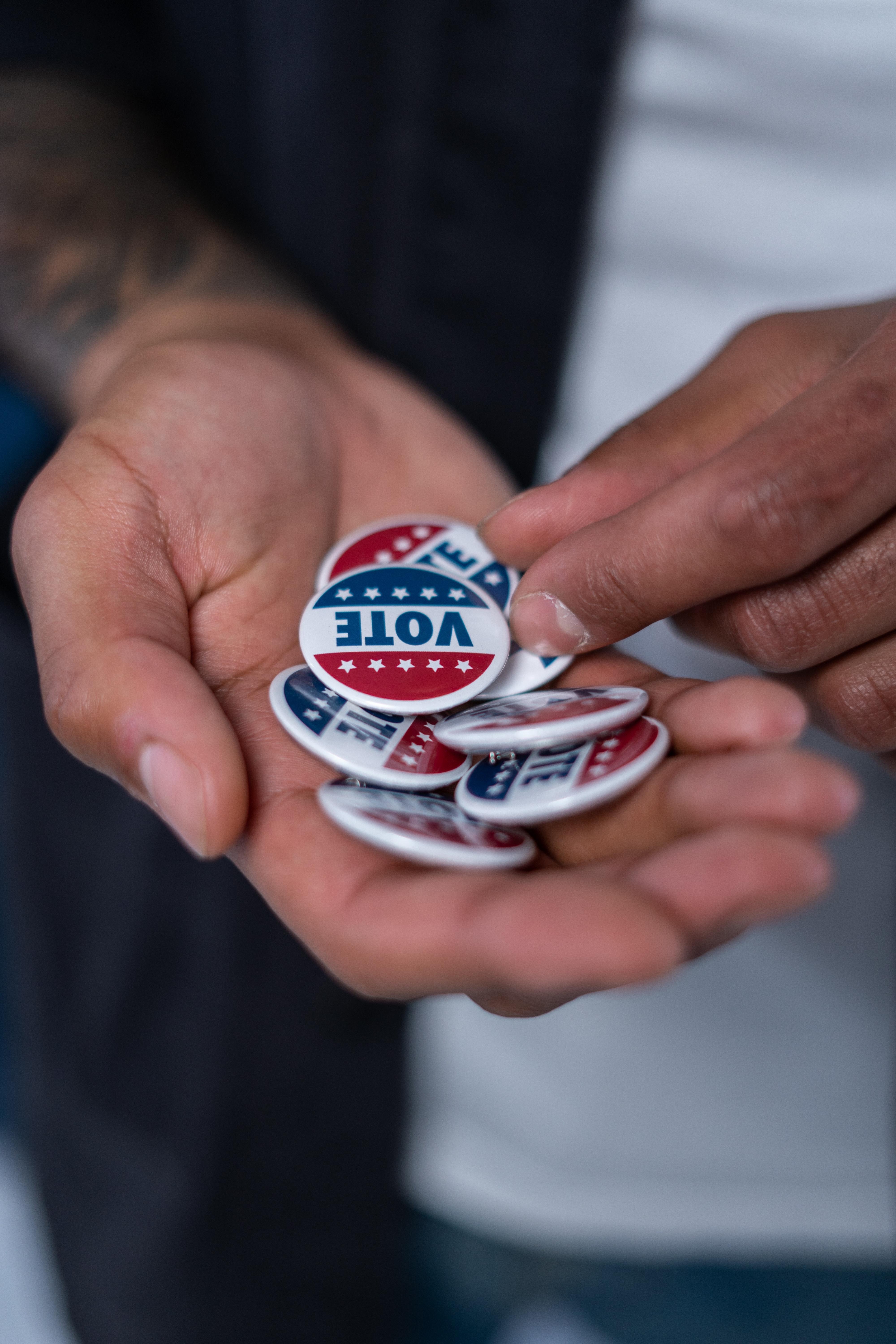 hands filled with buttons that say vote